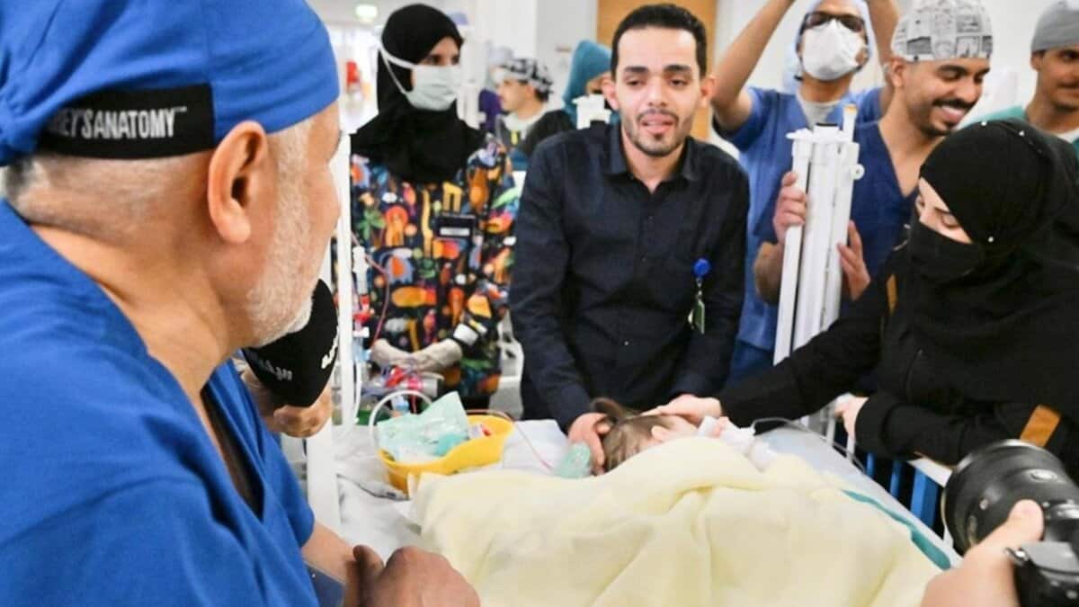 Doctors and family members surround one of the separated Syrian conjoined twins in a hospital room after the successful surgery.