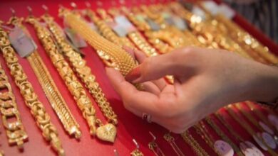 A shopper examines gold jewellery at a store display.