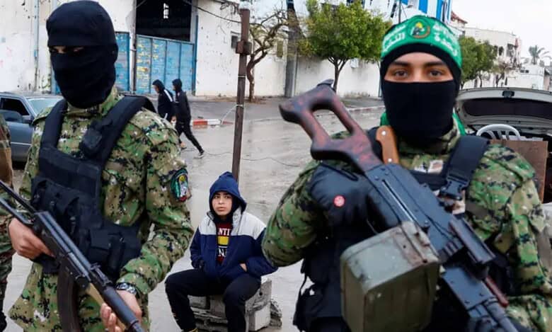 Armed Hamas militants in camouflage and masks stand guard on a street in Gaza.