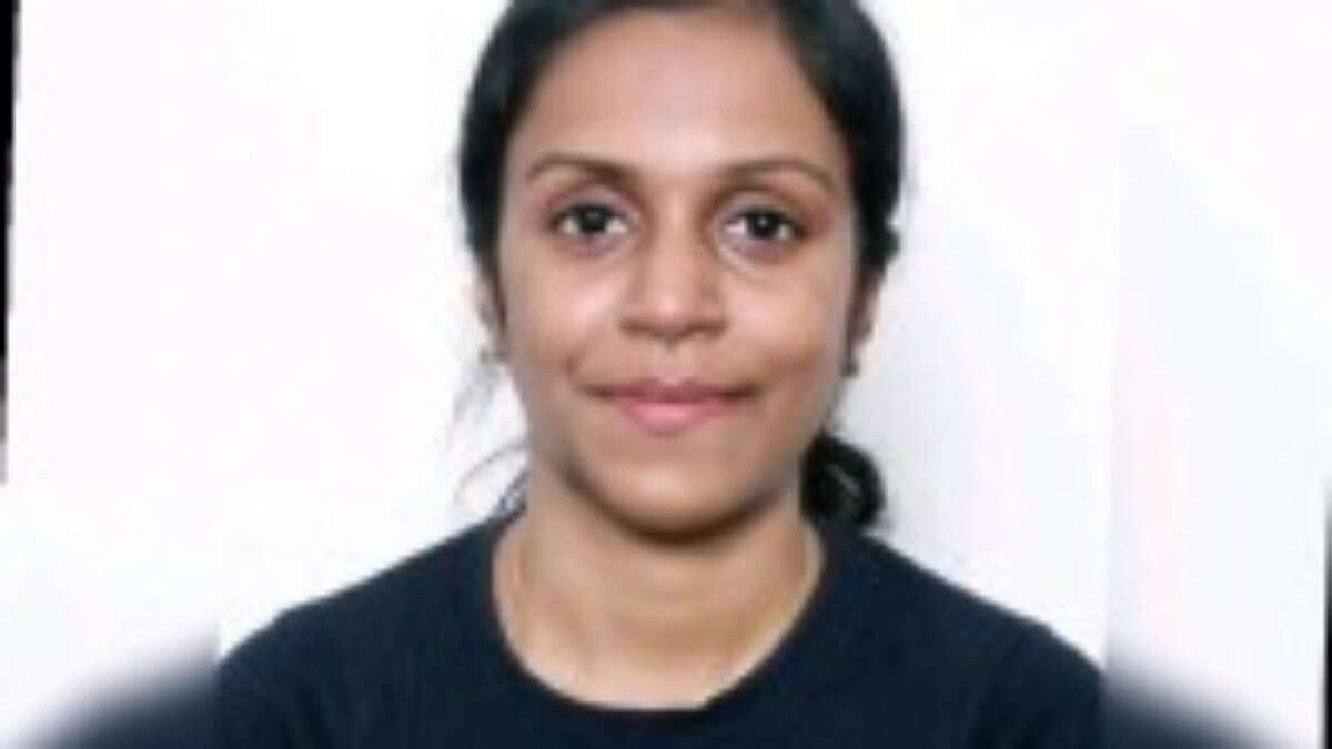 Sweety Stanly, smiling slightly, with a plain white background. She has tied-back hair and is wearing a dark top.