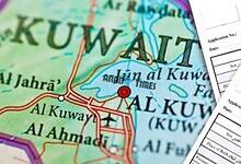 Map of Kuwait with visa application forms in the foreground.