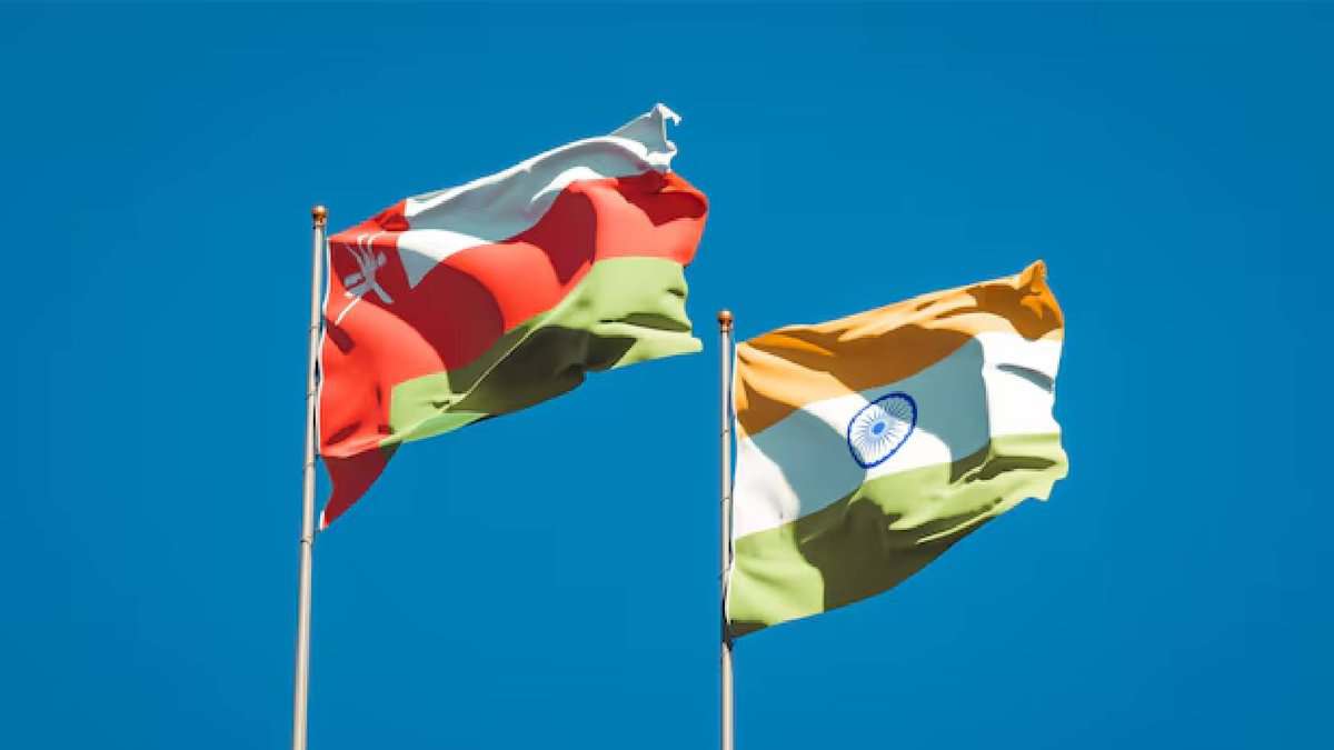 National flags of Oman and India waving against a clear blue sky, symbolising diplomatic and trade relations between the two nations.