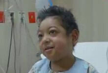 Smiling 7-year-old Saudi boy in hospital gown after heart transplant.