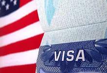 Close-up of a US visa page in a passport with the American flag in the background..