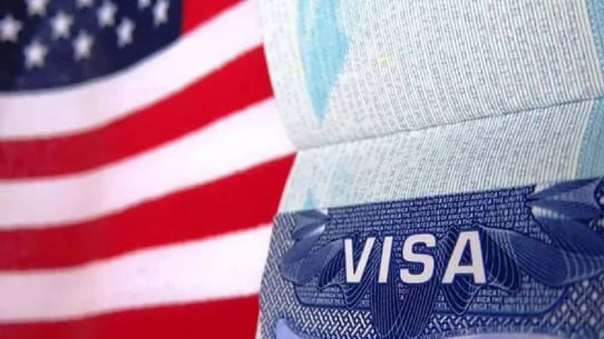 Close-up of a US visa page in a passport with the American flag in the background..