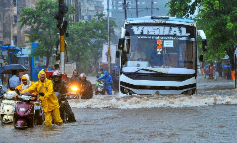 Commuters make way through a waterlogged road amid rainfall in Palghar in Maharashtra on Tuesday. (PTI Photo)