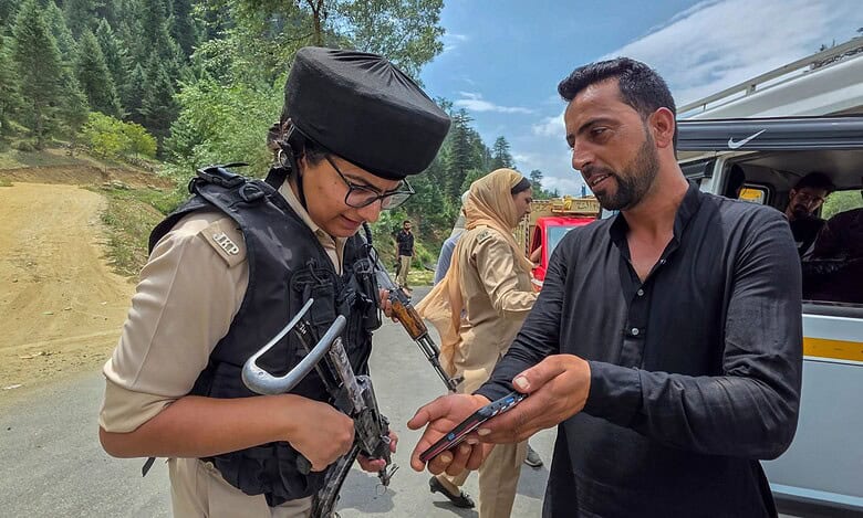 A J&K Police personnel checks documents of a commuter after security was beefed up ahead of Independence Day in Kupwara district (PTI Photo)