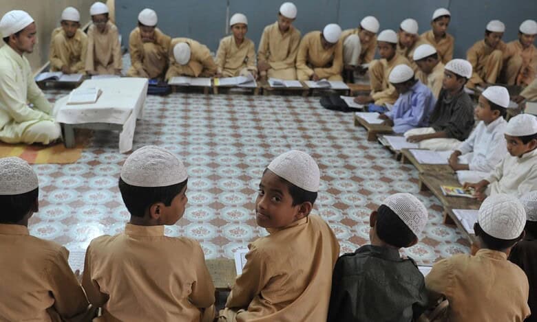 The image shows a madrasa with Muslim boys studying