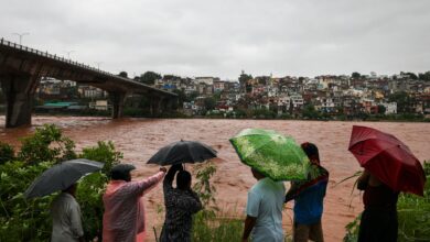People look at the swollen Tawi river amid rainfall in Jammu on Tuesday. The river has crossed the 20 feet danger mark in Udhampur district, while downstream in Jammu it is flowing currently below the alert level, according to officials. (PTI Photo)