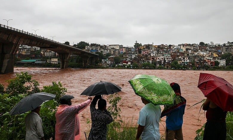 People look at the swollen Tawi river amid rainfall in Jammu on Tuesday. The river has crossed the 20 feet danger mark in Udhampur district, while downstream in Jammu it is flowing currently below the alert level, according to officials. (PTI Photo)