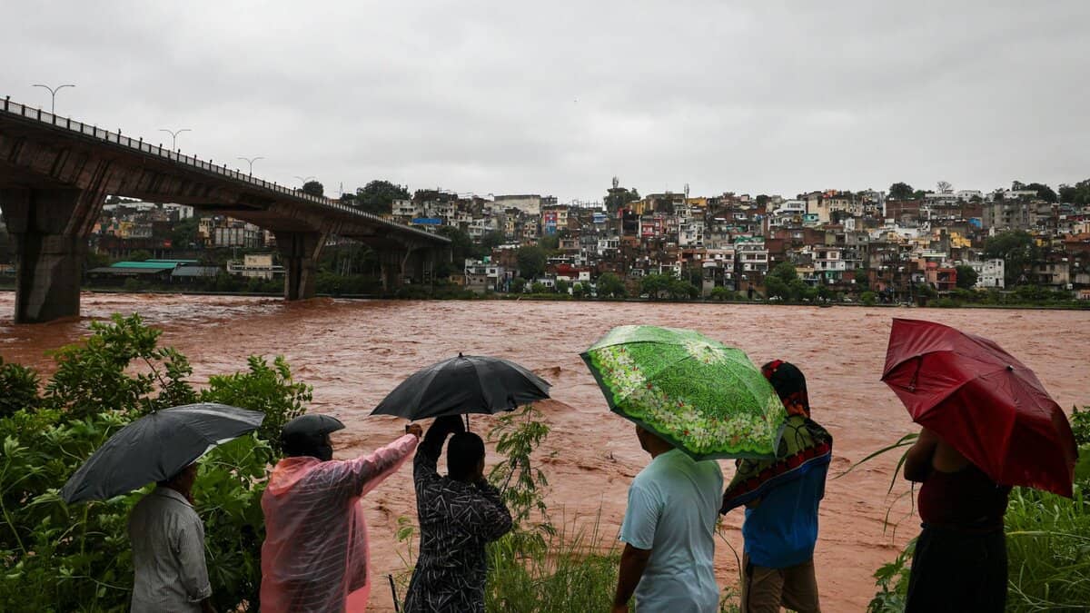 People look at the swollen Tawi river amid rainfall in Jammu on Tuesday. The river has crossed the 20 feet danger mark in Udhampur district, while downstream in Jammu it is flowing currently below the alert level, according to officials. (PTI Photo)