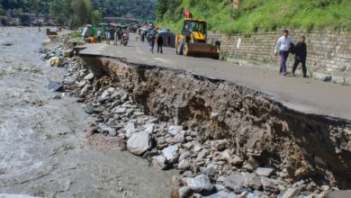 People walk over a portion of a road that was washed away by the Beas river flowing in spate following heavy rainfall in Kullu district, Himachal Pradesh. (PTI Photo)