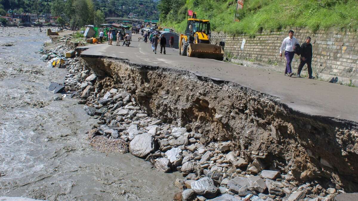 People walk over a portion of a road that was washed away by the Beas river flowing in spate following heavy rainfall in Kullu district, Himachal Pradesh. (PTI Photo)