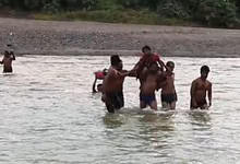 The image shows the villagers of a tribal hamlet in Kumram Bheem Asifabad district carrying an Anganwadi on shoulders across the stream as there was no medical help available on Wednesday, August 20, 2025.