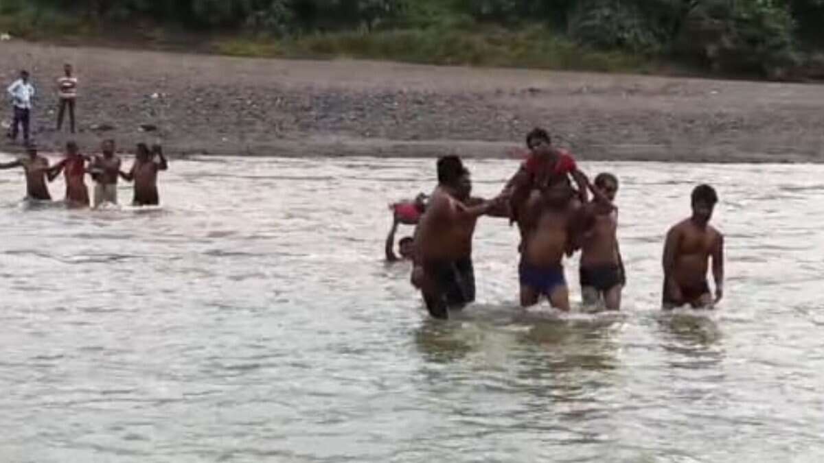 The image shows the villagers of a tribal hamlet in Kumram Bheem Asifabad district carrying an Anganwadi on shoulders across the stream as there was no medical help available on Wednesday, August 20, 2025.