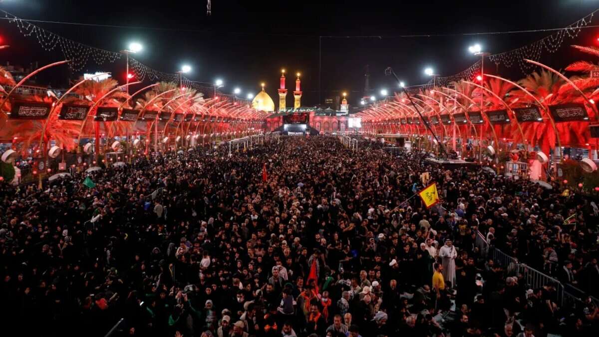 Crowds of Shiite worshippers gather in Karbala, Iraq, during the Arbaeen pilgrimage at night, with illuminated shrines in the background.