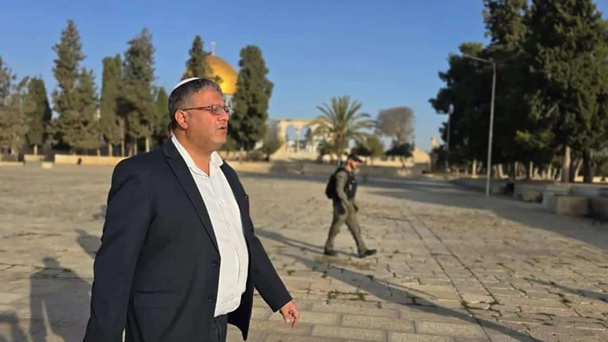 Israeli National Security Minister Itamar Ben-Gvir walks at Al-Aqsa Mosque compound under police guard, with Dome of the Rock in the background.