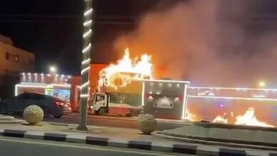 A burning truck near a petrol station in Saudi Arabia, with flames rising from its cabin.