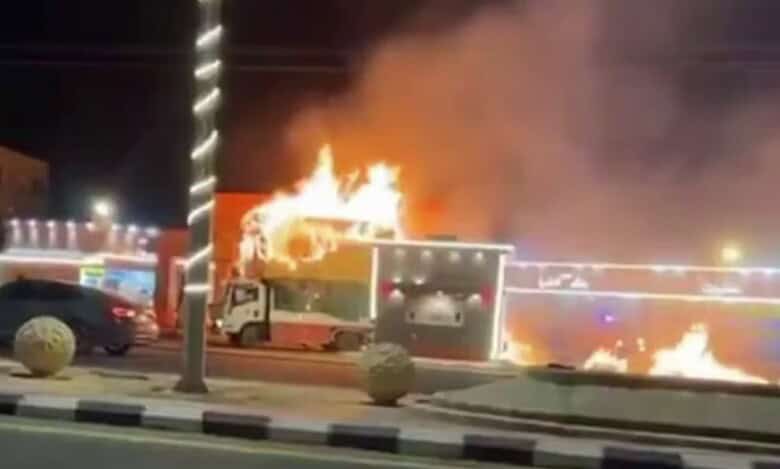 A burning truck near a petrol station in Saudi Arabia, with flames rising from its cabin.