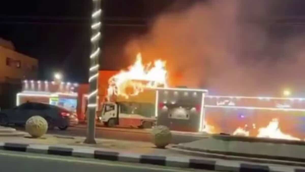 A burning truck near a petrol station in Saudi Arabia, with flames rising from its cabin.