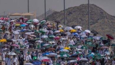 Haj pilgrims walking with colourful umbrellas under the sun in Mina, Saudi Arabia.