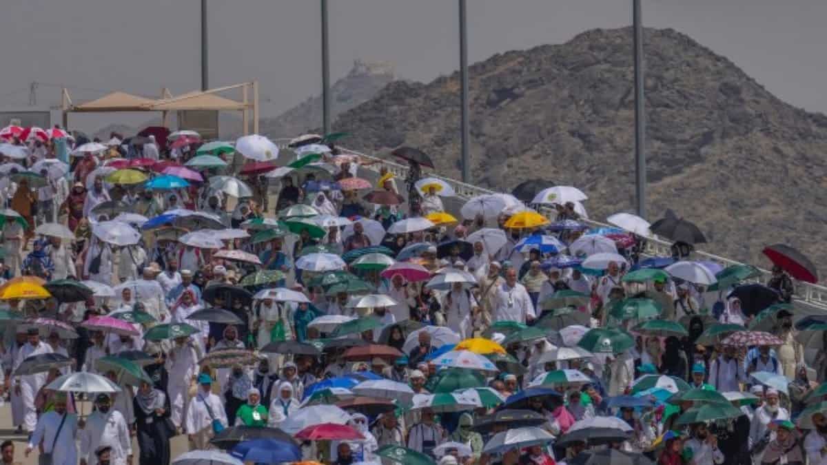 Haj pilgrims walking with colourful umbrellas under the sun in Mina, Saudi Arabia.