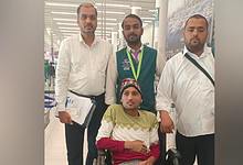 Indian expat in wheelchair at Saudi airport with embassy officials before flying home.