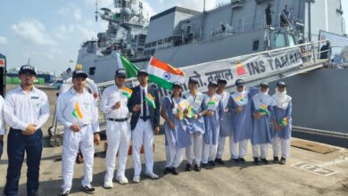 A group of Indian school students and Navy personnel holding Indian flags stand in front of INS Tamal during its port call in Jeddah, Saudi Arabia.