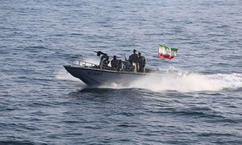 Iranian navy speedboat with soldiers and mounted gun sails during military exercise in open waters.