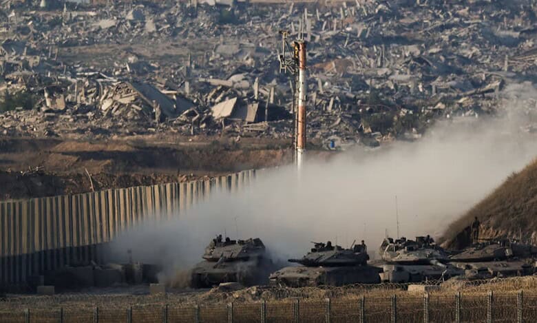 Israeli tanks manoeuvre near the Gaza border with destroyed buildings visible in the background, August 27, 2025.