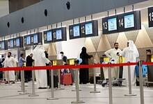 Passengers queue at check-in counters inside Kuwait International Airport.
