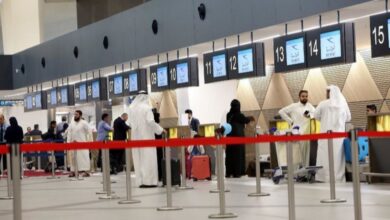 Passengers queue at check-in counters inside Kuwait International Airport.