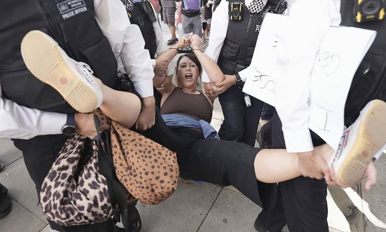 Police officers carry a protesting woman during a pro-Palestine Action demonstration in Parliament Square, London.