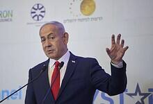 Israeli Prime Minister Benjamin Netanyahu gestures while addressing an audience at a political event.