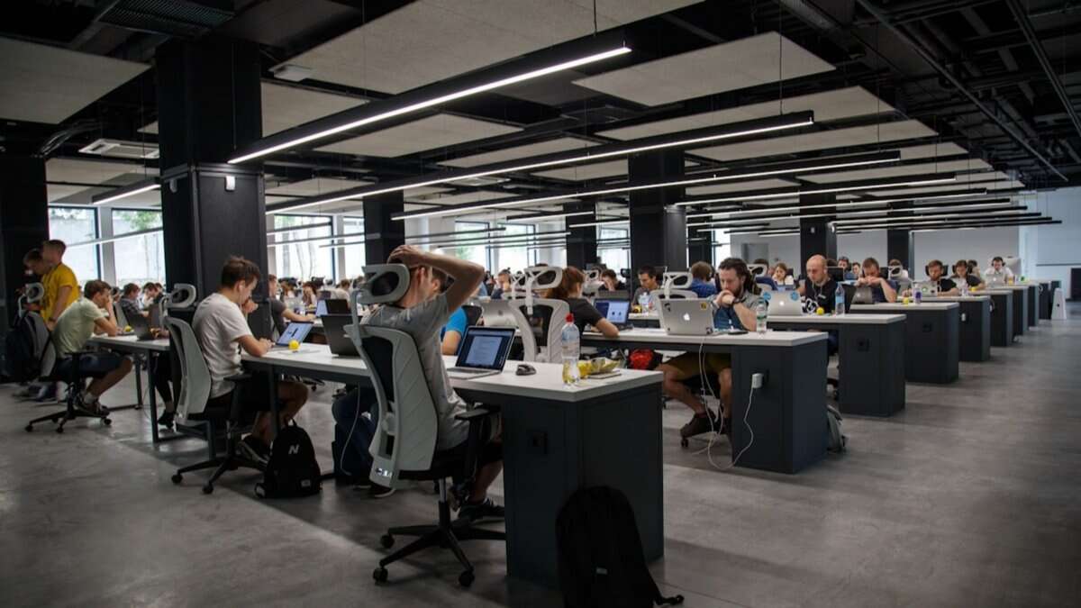 Representative image of a modern open-plan office with employees working on laptops.