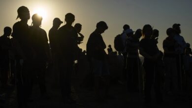 Silhouettes of Orthodox Jewish men standing together at sunset near the Gaza border.