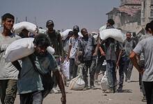 The image of Palestinians carrying sacks of flour from a humanitarian aid convoy in Gaza City, July 27, 2025.