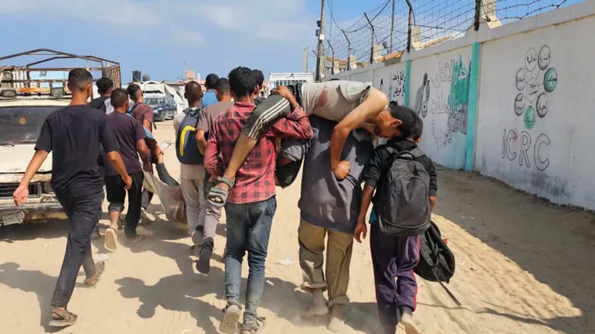 Palestinians carry wounded man near Gaza aid distribution point amid conflict.