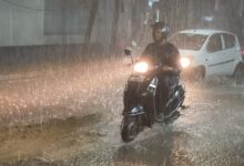 Image of rains in Hyderabad. A man rides his bike in heavy rains.