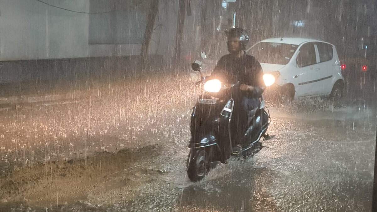 Image of rains in Hyderabad. A man rides his bike in heavy rains.