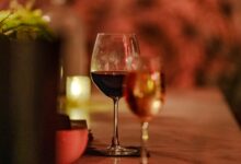 Glasses of wine on a dimly lit table with candlelight.
