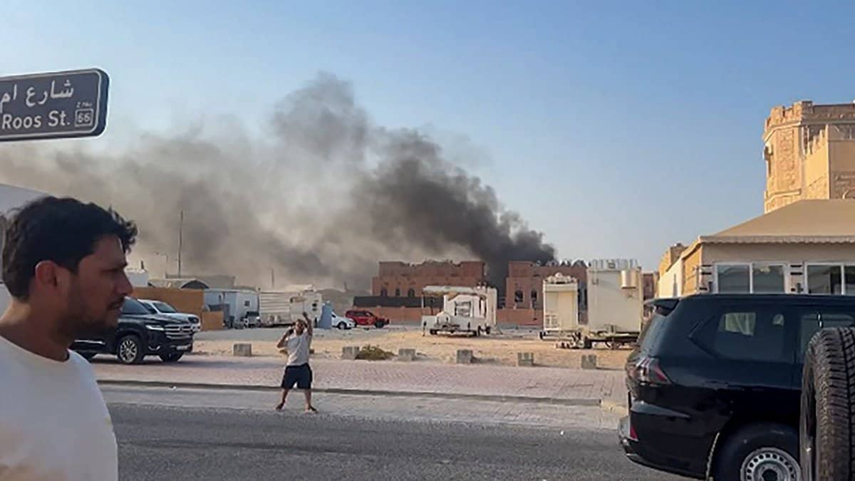 Smoke billows into the sky behind buildings in central Doha as people look on, following explosions in the Qatari capital on 9 September 2025.