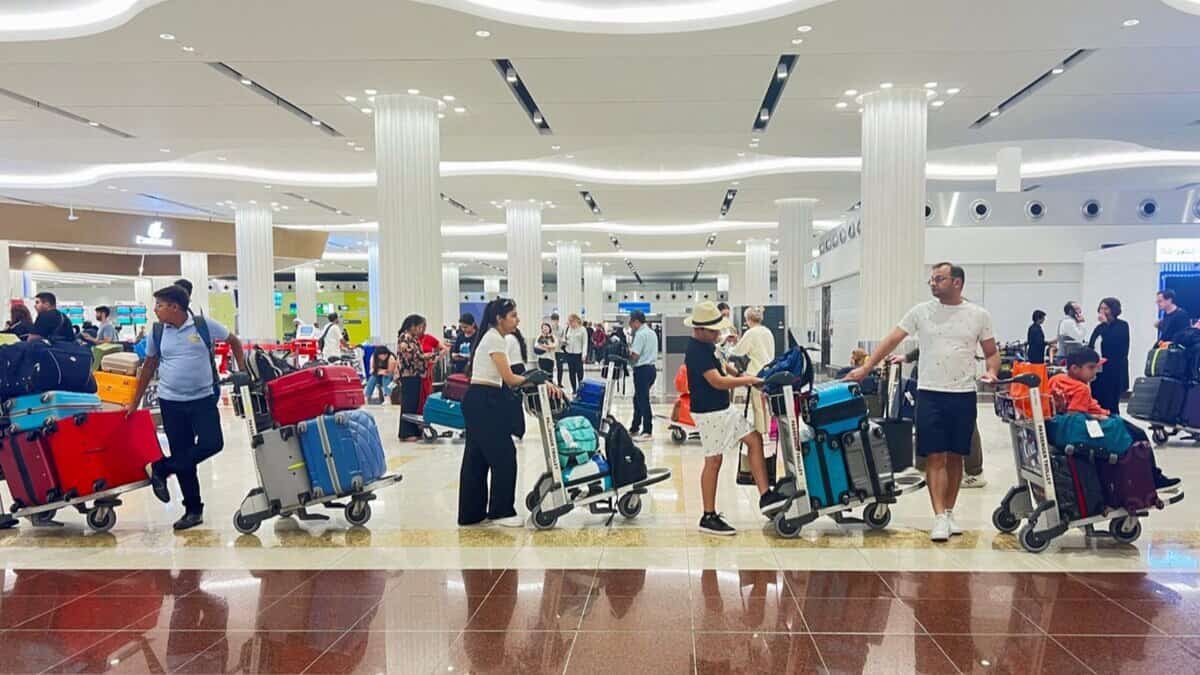 Passengers with luggage trolleys at Dubai International Airport terminal