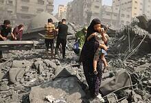 People walk through rubble and dust after Israeli air strikes destroyed buildings in Gaza City.