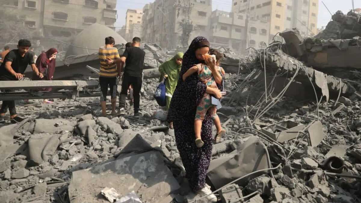People walk through rubble and dust after Israeli air strikes destroyed buildings in Gaza City.