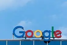 Google headquarters logo on building facade under clear blue sky.