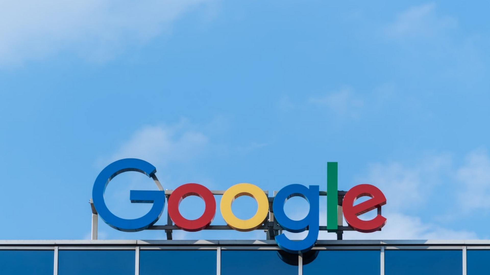 Google headquarters logo on building facade under clear blue sky.