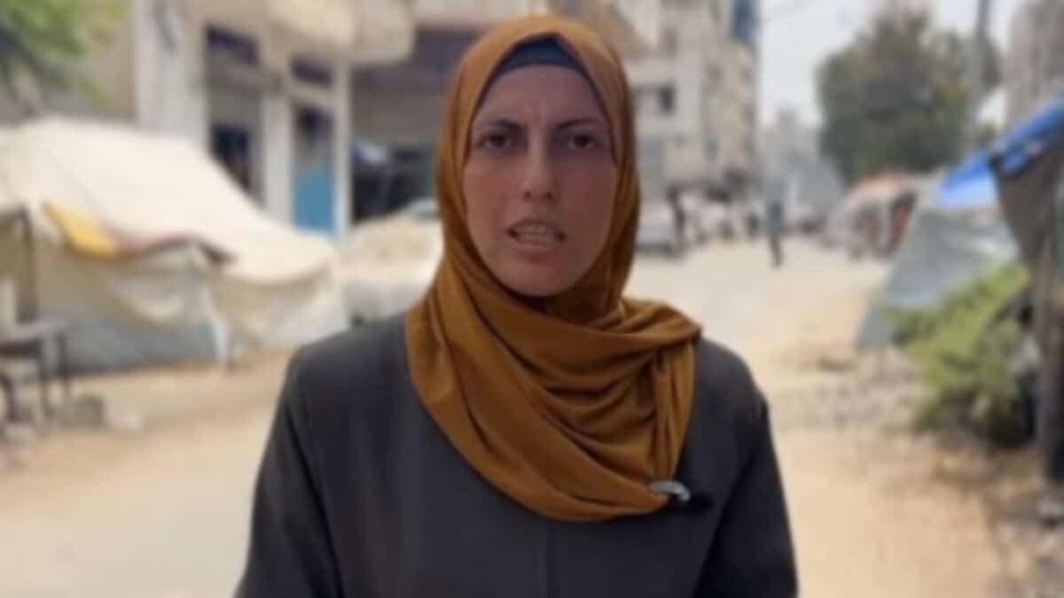 Photo of Palestinian journalist Islam Abed wearing a mustard-colored hijab, standing outdoors in Gaza City.