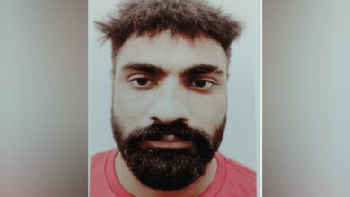 Close-up mugshot of Parminder Singh with a beard, short messy hair, and wearing a red shirt.