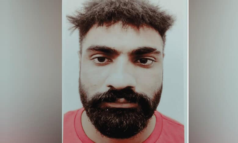 Close-up mugshot of Parminder Singh with a beard, short messy hair, and wearing a red shirt.